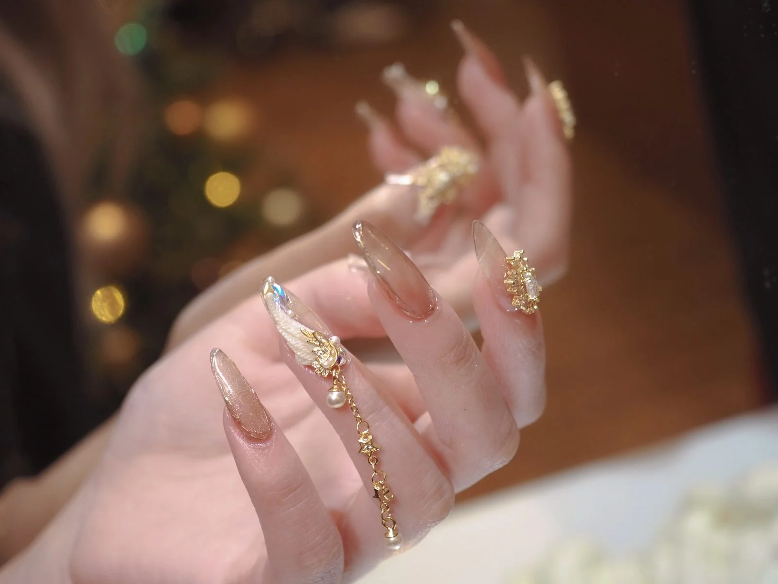 Clear stiletto nails with gold filigree, pearls and dangling chain charm